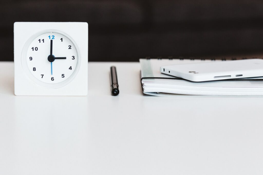 desk clock sitting next to a pen and papers